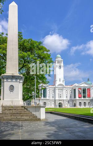 L'obelisco Dalhousie di John Turnbull Thomson rispecchia l'alta torre dell'orologio bianco del Victoria Theatre and Concert Hall in Empress Place, Singapore. Foto Stock