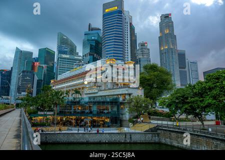 Lo storico Fullerton Hotel si trova sotto i torreggianti grattacieli del quartiere finanziario di Singapore mentre il sole tramonta sul fiume Singapore. Foto Stock