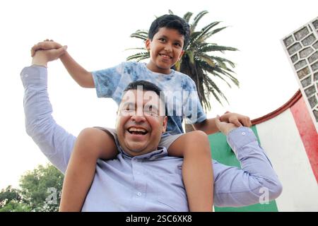 Il padre single divorziato porta il figlio latino di 9 anni dalla pelle scura sulle spalle, gioca e trascorre del tempo insieme per celebrare la festa del papà Foto Stock