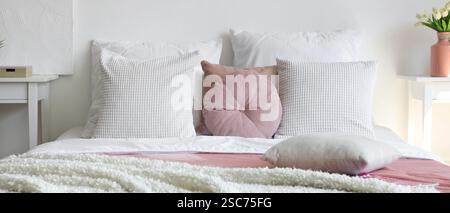 Letto confortevole con coperta bianca e cuscini in camera da letto Foto Stock