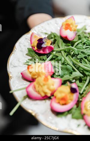 Un piatto di insalate splendidamente allestito presenta fiori commestibili colorati in cima a verdi, con elementi gourmet che mettono in risalto la creatività in un ristorante elegante Foto Stock
