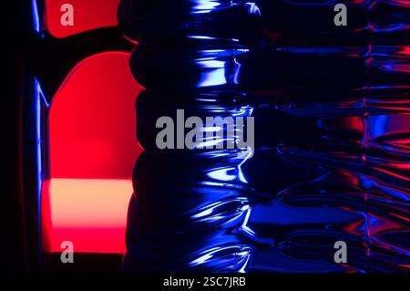 Primo piano astratto di una bottiglia d'acqua in plastica con riflessi di luce colorati Foto Stock