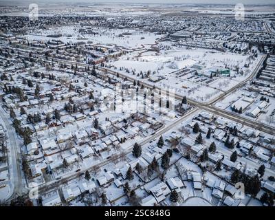 Paesaggio urbano innevato con case e auto. La neve copre il terreno e le case sono coperte di neve Foto Stock