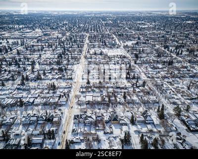 Paesaggio urbano innevato con case e alberi. Il cielo è nuvoloso e la neve copre il terreno Foto Stock