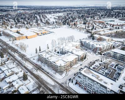 Paesaggio urbano innevato con un grande complesso di appartamenti nel centro. La neve copre il terreno e gli edifici, dando alla scena un sereno e sereno Foto Stock
