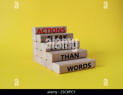 Le azioni parlano più forte del simbolo delle parole. I blocchi di legno con le parole le azioni parlano più forte delle parole. Bellissimo sfondo giallo. Business e azioni co Foto Stock