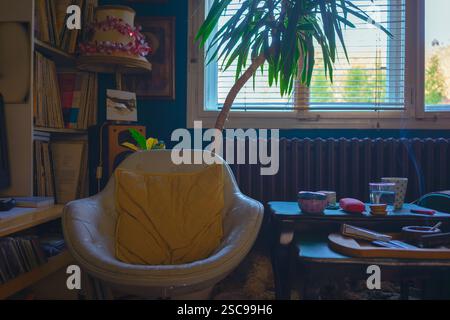 Una vecchia e comoda poltrona accanto alla finestra, sullo sfondo ci sono registrazioni grammofoniche sugli scaffali, un radiatore e una vecchia lampada retrò. Foto Stock