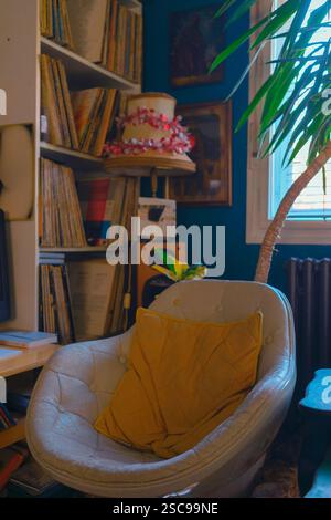 Una vecchia e comoda poltrona accanto alla finestra, sullo sfondo ci sono registrazioni grammofoniche sugli scaffali, un radiatore e una vecchia lampada retrò. Foto Stock