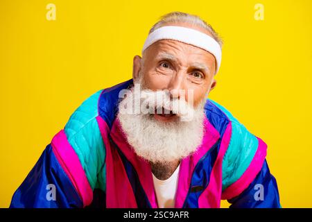 Poster fotografico del bellissimo nonno sportivo sembra infastidito la fotocamera indossa abbigliamento sportivo vintage alla moda isolato su sfondo giallo Foto Stock