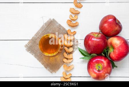 Succo di mela biologico fresco in tazza di vetro con mele mature rosse e secche, frutta fresca concetto di bevanda fredda Foto Stock