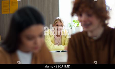 Tre compagni di scuola studenti alunni che studiano in classe l'uomo sfuocato donna maschile insieme imparano il ragazzo ridendo sorridendo donne positive uomini Foto Stock