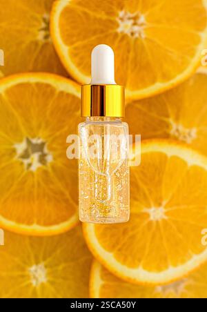 Siero con vitamina C in flacone trasparente. Sfondo di arance. Concetto di bellezza e salute. Mockup per il tuo progetto con spazio di copia Foto Stock