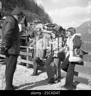 Uomo di mangiare il ghiaccio e in possesso di una fotocamera a pellicola dietro la schiena mentre in piedi di fronte a tre donne. Foto Stock
