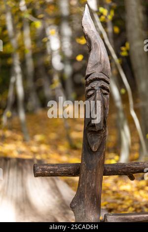 una testa scolpita in legno da un artista sconosciuto sullo sfondo di una foresta dai colori autunnali Foto Stock