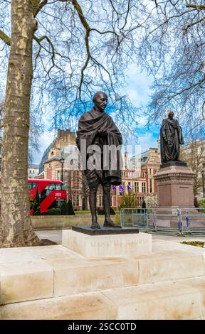 Splendida vista della statua del Mahatma Gandhi in Parliament Square, Westminster, Londra, e sullo sfondo su un piedistallo di granito rosso si erge il... Foto Stock