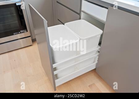 Una cucina con un forno argentato e un cestino bianco. Il cestino si trova in un cassetto con altri due cestini Foto Stock