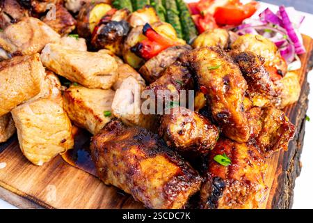 Un piatto ben disposto presenta una varietà di carni alla griglia e verdure colorate. Questo banchetto all'aperto è perfetto per riunioni e riunioni Foto Stock