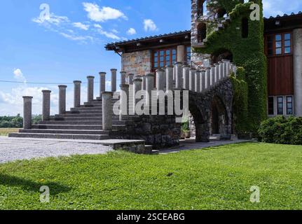 Gradini rustici in pietra che conducono ad una maestosa porta ad arco di una chiesa storica, immersa nel verde lussureggiante Foto Stock