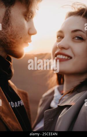 Giovane coppia al tramonto, sorridendo affettuosamente, catturando un momento caldo e intimo Foto Stock
