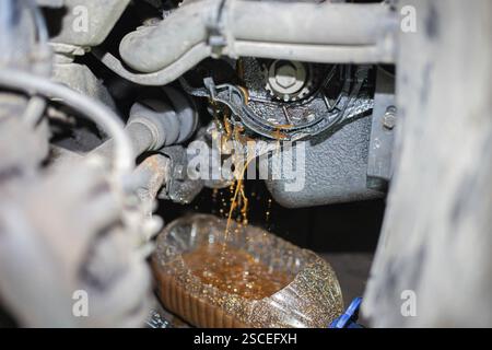 Perdite di olio dal motore di una vettura in un contenitore durante la manutenzione Foto Stock