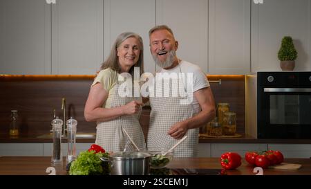 Famiglia di mezza età caucasica dai capelli grigi pensionati coppia proprietari di casa donna moglie e marito anziani nonni maturi che si coccolano abbracciando guardando ciascuno Foto Stock