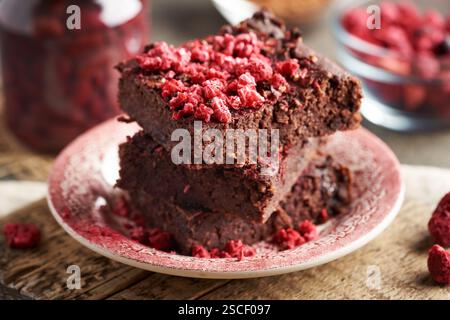 Brownie senza glutine fatti in casa, realizzati con fagioli rossi, fiocchi d'avena e cioccolato, ricoperti di lamponi liofilizzati Foto Stock