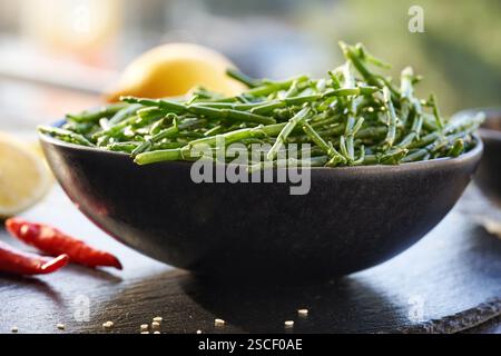 Salicornia verde fresca o alga di glasswort in un recipiente con semi di sesamo, peperoncino e limone Foto Stock