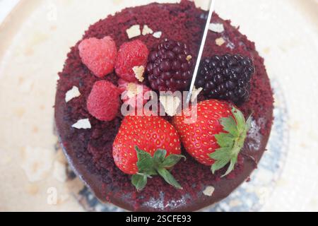 Deliziosa torta di velluto rosso condita con frutti di bosco freschi e panna Foto Stock