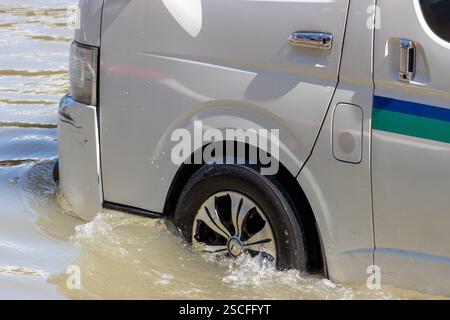 Un minivan attraversa una strada allagata della città Foto Stock