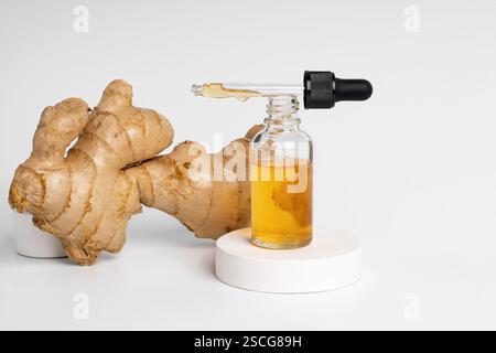 Siero o olio giallo zenzero in un flacone contagocce per viso o corpo in piedi su un podio di cemento bianco Foto Stock