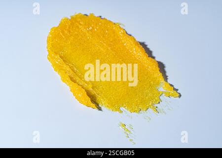 Scrub giallo per la cura della pelle, striscio di campioni su sfondo blu. Primo piano con strisciatura di un prodotto cosmetico di bellezza testurizzato Foto Stock
