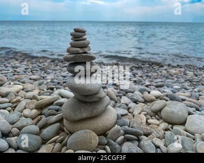 Pietre impilate nella piramide in piedi sul mare che simboleggiano la tranquillità e il concetto buddhista Foto Stock