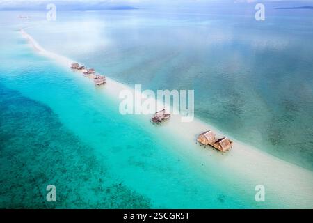 Vista aerea di case tradizionali in legno, baite dei pescatori bajau su pilastri su una riva di sabbia in una laguna nel mezzo di un mare, sulawesi, indonesia Foto Stock