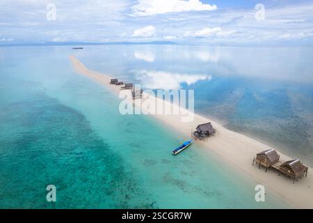 Vista aerea delle tradizionali case bajau in legno, dei cottage dei pescatori su palafitte su una riva di sabbia in una laguna nel mezzo di un mare, sulawesi, indonesia Foto Stock