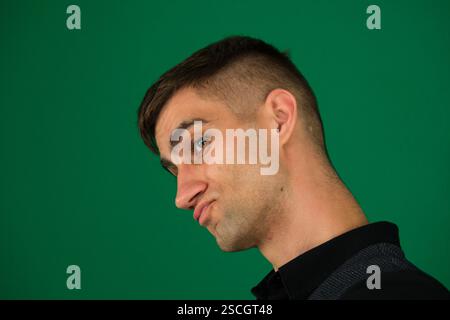 Ritratto di un bell'uomo caucasico in costume formale che guarda la macchina fotografica sorridendo con le emozioni toothy di un bel ragazzo uomo su uno sfondo verde cromakey primo piano capelli scuri giovane uomo Foto Stock