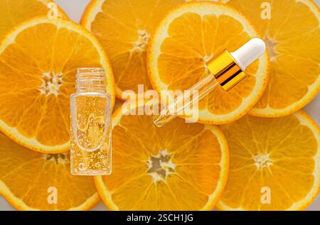 Siero con vitamina C in un flacone trasparente aperto. Sfondo di arance. Concetto di bellezza e salute. Mockup per il tuo progetto con spazio di copia Foto Stock