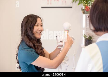 Medico che mostra al paziente lo scheletro del collo cervicale Foto Stock