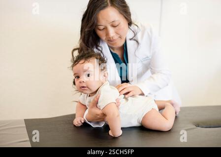 Il bambino è steso sul tavolo d'esame mentre il medico lo valuta Foto Stock