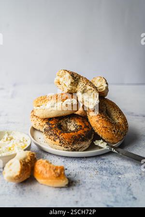 Piatto di bagel assortiti con formaggio spalmabile su sfondo leggero. Foto Stock