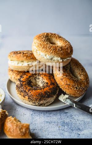 Primo piano di una pila di bagel assortiti con formaggio spalmabile. Foto Stock