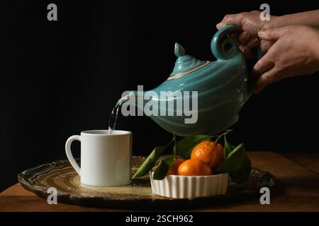 Teiera blu e arance sul piatto Foto Stock