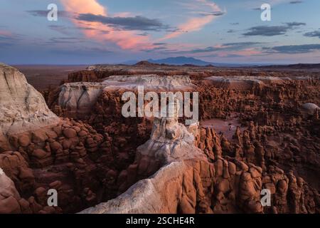 Splendida fotografia aerea che cattura il Goblin Valley State Park, Utah, al tramonto con le sue formazioni rocciose uniche sotto un cielo vibrante. Foto Stock