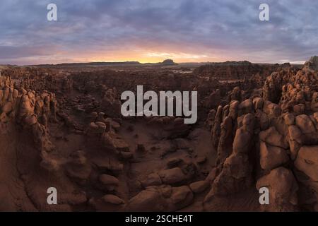 Una fotografia aerea panoramica che cattura le formazioni rocciose uniche e il vasto paesaggio del Goblin Valley State Park, Utah, durante il tramonto. Foto Stock