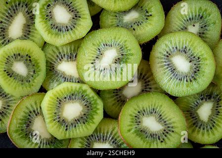 Una vista ravvicinata di più fette di kiwi fresche che rivelano il loro vibrante colore verde e il caratteristico motivo dei semi, evidenziando la loro succosa e rinfrescante Foto Stock