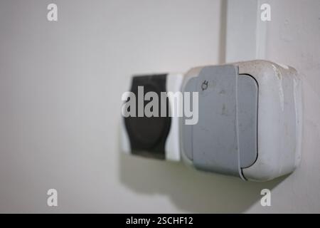 Due prese di corrente sono montate su una semplice parete bianca. Uno è rotondo e l'altro è quadrato, mostrando design e funzionalità semplici in una spa interna Foto Stock