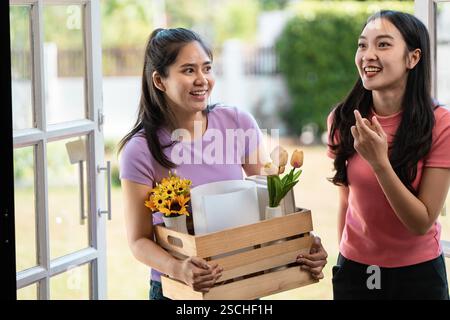 Diverse coppie di donne che trasportano con gioia fiori e disimballano scatole nella loro nuova casa. Foto Stock