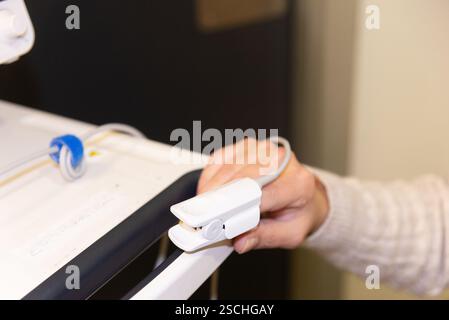 Una donna matura è sottoposta a un test di pulsossimetria in un ambiente ospedaliero, una procedura comune per misurare la saturazione di ossigeno nel sangue. Foto Stock