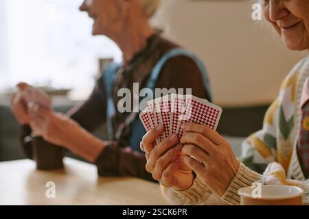 Primo piano medio di una donna anziana irriconoscibile che tiene le carte Foto Stock