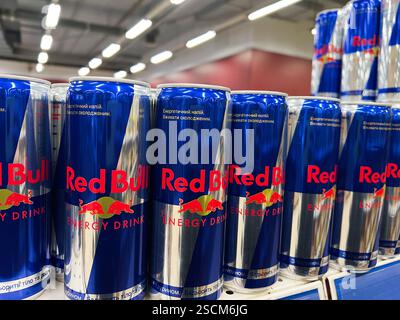 Kiev, Ucraina - 4 febbraio 2025: Fila di lattine per bevande energetiche Red Bull esposte ordinatamente sugli scaffali Foto Stock