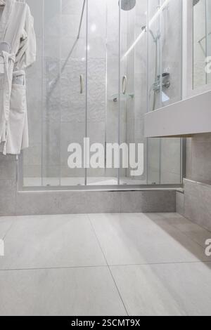 Bagno luminoso ed elegante con box doccia in vetro, WC a parete e piastrelle effetto marmo per un aspetto elegante e lussuoso. Foto Stock